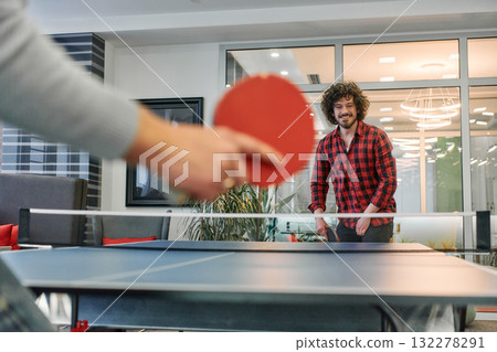 Business colleagues take a break from work to enjoy a game of table tennis, fostering teamwork and camaraderie in the workplace Business colleagues take a break from work to enjoy a game of table tennis, fostering teamwork and camaraderie in the workplace 132278291