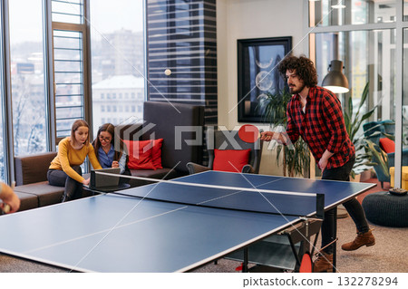 Business colleagues take a break from work to enjoy a game of table tennis, fostering teamwork and camaraderie in the workplace Business colleagues take a break from work to enjoy a game of table tennis, fostering teamwork and camaraderie in the workplace 132278294