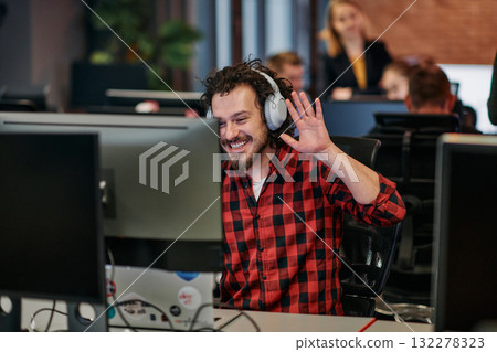 Joyful Collaboration: A Man Embracing Remote Work with Enthusiastic Gestures in a Coworking Space. 132278323
