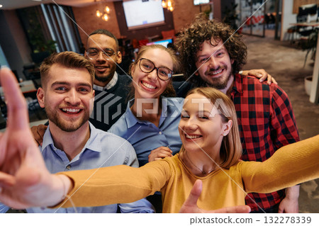A diverse group of business professionals take a break from their tasks in a modern startup office to capture a creative selfie, showcasing teamwork and a vibrant workplace culture A diverse group of business professionals take a break from their tasks in a modern startup office to capture a creative selfie, showcasing teamwork and a vibrant workplace culture 132278339