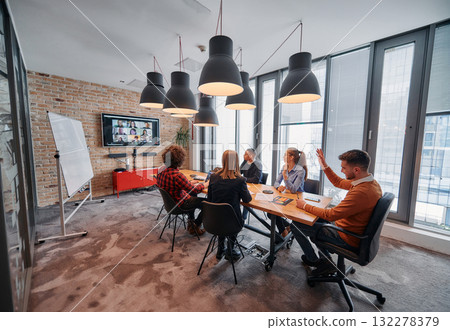 In the vibrant ambiance of a modern startup office, a diverse team of business professionals engage in discussions on various projects and develop new business strategies, epitomizing creativity and 132278379