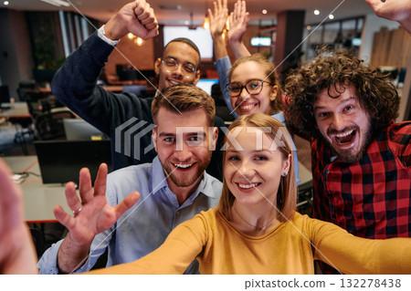 A diverse group of business professionals take a break from their tasks in a modern startup office to capture a creative selfie, showcasing teamwork and a vibrant workplace culture 132278438