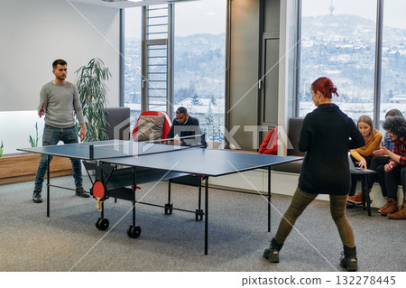 Business colleagues take a break from work to enjoy a game of table tennis, fostering teamwork and camaraderie in the workplace 132278445