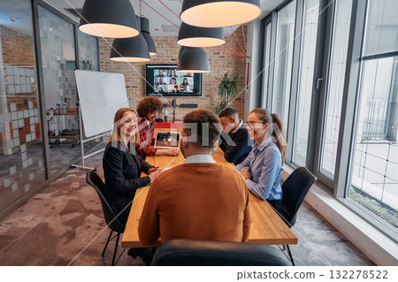 In the vibrant ambiance of a modern startup office, a diverse team of business professionals engage in discussions on various projects and develop new business strategies, epitomizing creativity and 132278522