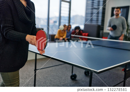 Business colleagues take a break from work to enjoy a game of table tennis, fostering teamwork and camaraderie in the workplace Business colleagues take a break from work to enjoy a game of table tennis, fostering teamwork and camaraderie in the workplace 132278581