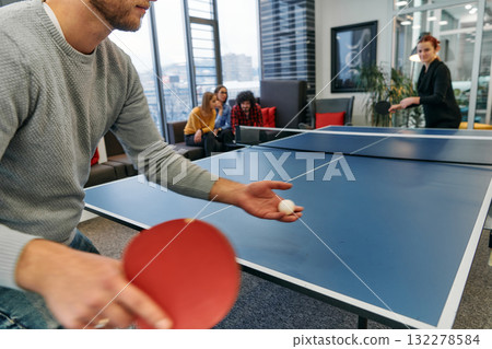 Business colleagues take a break from work to enjoy a game of table tennis, fostering teamwork and camaraderie in the workplace Business colleagues take a break from work to enjoy a game of table tennis, fostering teamwork and camaraderie in the workplace 132278584