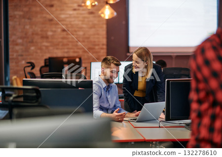 Business colleagues, a man and a woman, engage in discussing business strategies while attentively gazing at a computer monitor, epitomizing collaboration and innovation Business colleagues, a man and a woman, engage in discussing business strategies while attentively gazing at a computer monitor, epitomizing collaboration and innovation 132278610