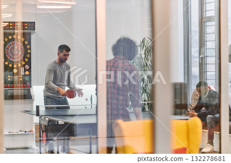 Business colleagues take a break from work to enjoy a game of table tennis, fostering teamwork and camaraderie in the workplace Business colleagues take a break from work to enjoy a game of table tennis, fostering teamwork and camaraderie in the workplace 132278681