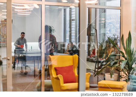 Business colleagues take a break from work to enjoy a game of table tennis, fostering teamwork and camaraderie in the workplace 132278689