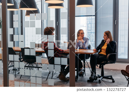 In the dynamic hustle and bustle of a business environment, a group of young business professionals walk down the corridor next to their office, while their colleagues collaborate inside, symbolizing In the dynamic hustle and bustle of a business environment, a group of young business professionals walk down the corridor next to their office, while their colleagues collaborate inside, symbolizing 132278727
