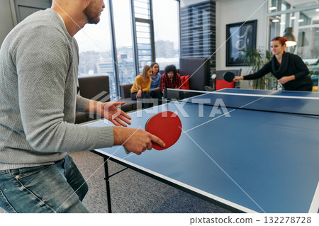 Business colleagues take a break from work to enjoy a game of table tennis, fostering teamwork and camaraderie in the workplace Business colleagues take a break from work to enjoy a game of table tennis, fostering teamwork and camaraderie in the workplace 132278728