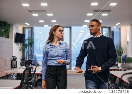 Dynamic Business Collaboration: Blonde Businesswoman and African American Colleague in Modern Office Setting. 132278768