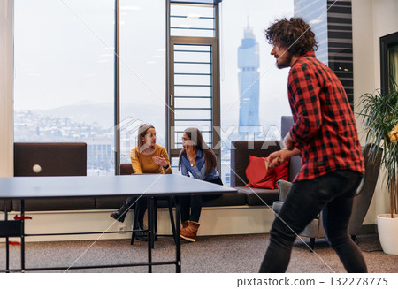 Business colleagues take a break from work to enjoy a game of table tennis, fostering teamwork and camaraderie in the workplace 132278775