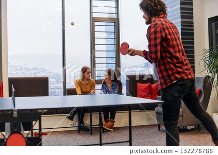 Business colleagues take a break from work to enjoy a game of table tennis, fostering teamwork and camaraderie in the workplace Business colleagues take a break from work to enjoy a game of table tennis, fostering teamwork and camaraderie in the workplace 132278788