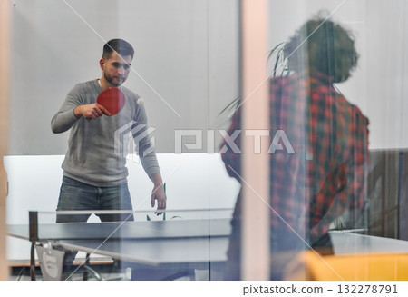 Business colleagues take a break from work to enjoy a game of table tennis, fostering teamwork and camaraderie in the workplace 132278791