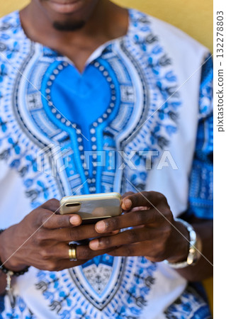 African American Teenager in Traditional Sudanese Attire Engaged with Smartphone 132278803