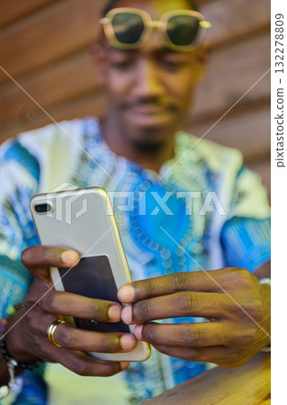 African American Teenager in Traditional Sudanese Attire Engaged with Smartphone African American Teenager in Traditional Sudanese Attire Engaged with Smartphone 132278809