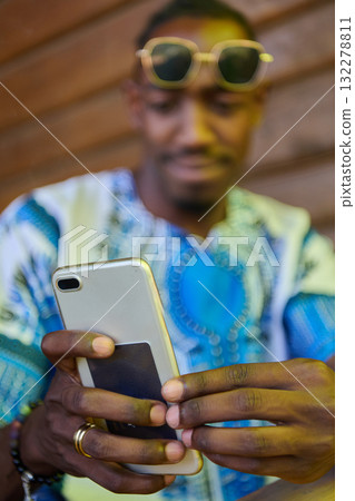 African American Teenager in Traditional Sudanese Attire Engaged with Smartphone African American Teenager in Traditional Sudanese Attire Engaged with Smartphone 132278811