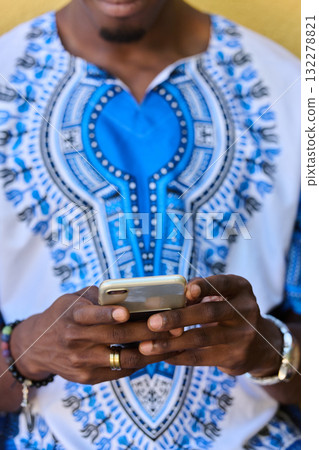African American Teenager in Traditional Sudanese Attire Engaged with Smartphone African American Teenager in Traditional Sudanese Attire Engaged with Smartphone 132278821