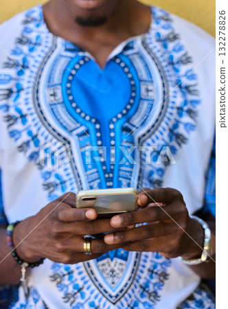 African American Teenager in Traditional Sudanese Attire Engaged with Smartphone 132278826