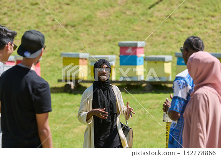A diverse group of young friends and entrepreneurs explore small honey production businesses in the natural setting of the countryside. 132278866