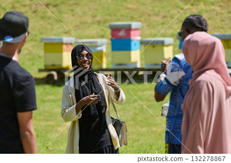 A diverse group of young friends and entrepreneurs explore small honey production businesses in the natural setting of the countryside. 132278867