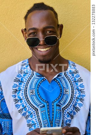 African American Teenager in Traditional Sudanese Attire Engaged with Smartphone 132278883