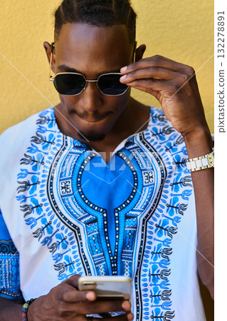 African American Teenager in Traditional Sudanese Attire Engaged with Smartphone African American Teenager in Traditional Sudanese Attire Engaged with Smartphone 132278891