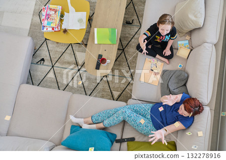 Top View of Mother and Daughter Enjoying a Fun Board Game on the Couch at Home Top View of Mother and Daughter Enjoying a Fun Board Game on the Couch at Home 132278916