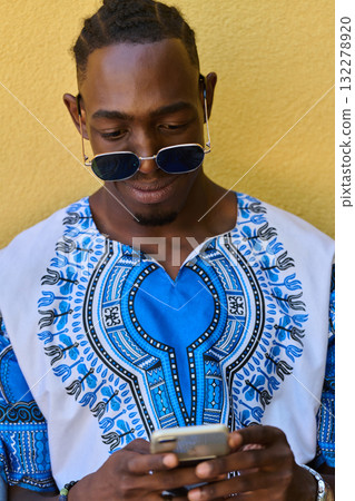 African American Teenager in Traditional Sudanese Attire Engaged with Smartphone 132278920