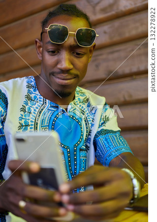 African American Teenager in Traditional Sudanese Attire Engaged with Smartphone African American Teenager in Traditional Sudanese Attire Engaged with Smartphone 132278922
