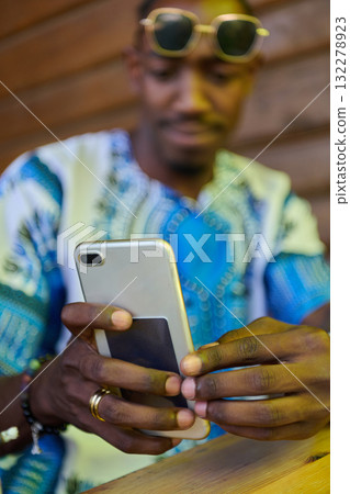 African American Teenager in Traditional Sudanese Attire Engaged with Smartphone 132278923