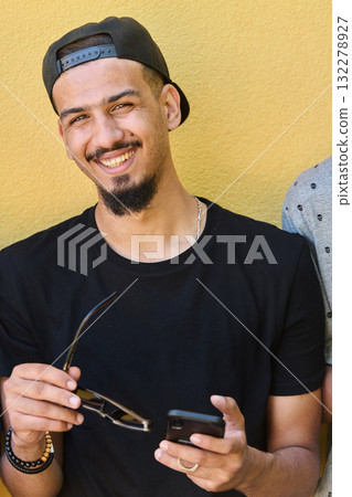 Close Up Portrait of Smiling Sudanese Teenager with Broad Smile, Chin, and Cap Using Smartphone Close Up Portrait of Smiling Sudanese Teenager with Broad Smile, Chin, and Cap Using Smartphone 132278927