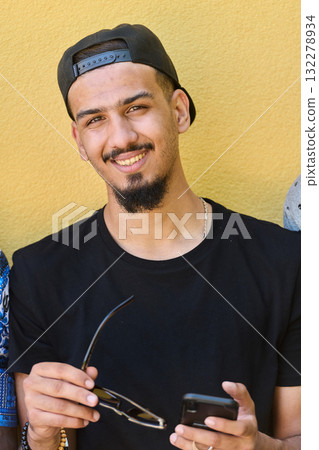 Close Up Portrait of Smiling Sudanese Teenager with Broad Smile, Chin, and Cap Using Smartphone Close Up Portrait of Smiling Sudanese Teenager with Broad Smile, Chin, and Cap Using Smartphone 132278934