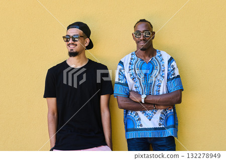 Two Male Friends: African American Teenager in Sudanese Traditional Attire Leaning Against Yellow Wall Two Male Friends: African American Teenager in Sudanese Traditional Attire Leaning Against Yellow Wall 132278949