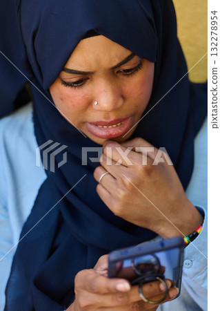 Digital Connection: Close-up Portrait of a Middle Eastern Teenage Muslim Girl Using Smartphone Digital Connection: Close-up Portrait of a Middle Eastern Teenage Muslim Girl Using Smartphone 132278954