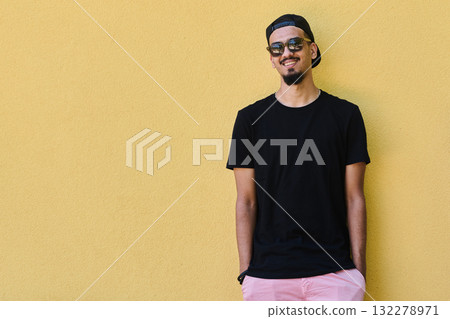Middle Eastern Teenager Leaning Against Yellow Wall in Casual Attire Middle Eastern Teenager Leaning Against Yellow Wall in Casual Attire 132278971