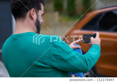 Capturing the Moment: A Man Photographs His Car for Sale to Share Online 132278997