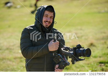 A skilled videographer, equipped with professional gear, captures the essence of nature's beauty, expertly documenting the scenic landscape in a cinematic masterpiece that reflects the seamless blend 132279058