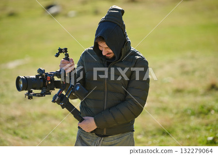 A skilled videographer, equipped with professional gear, captures the essence of nature's beauty, expertly documenting the scenic landscape in a cinematic masterpiece that reflects the seamless blend 132279064