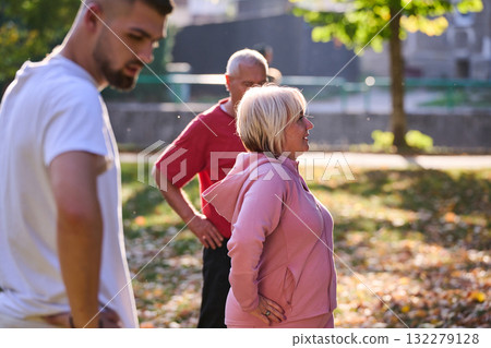 A group of seniors follows a trainer, engaging in outdoor exercises in the park, as they collectively strive to maintain vitality and well-being, embracing an active and health-conscious lifestyle in A group of seniors follows a trainer, engaging in outdoor exercises in the park, as they collectively strive to maintain vitality and well-being, embracing an active and health-conscious lifestyle in 132279128