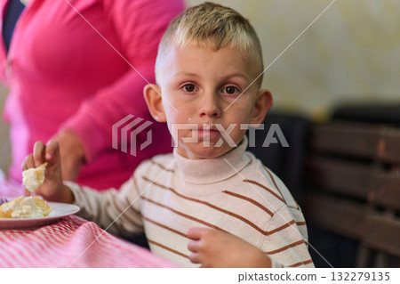 A young boy savors his breakfast, indulging in a wholesome meal that radiates the joy of a nutritious start to the day A young boy savors his breakfast, indulging in a wholesome meal that radiates the joy of a nutritious start to the day 132279135