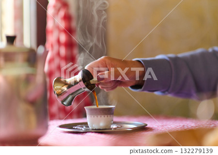 Elderly woman savors the serenity of the morning as she enjoys a cup of coffee on the porch of her rustic cottage, finding solace in the simplicity of nature and contemplative moments 132279139