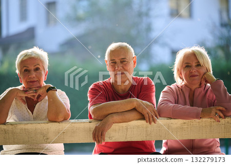 A group of elderly individuals, including a senior man and two older women, sits in a park on a sunny autumn day, embodying the concept of healthy aging through companionship, relaxation, and outdoor A group of elderly individuals, including a senior man and two older women, sits in a park on a sunny autumn day, embodying the concept of healthy aging through companionship, relaxation, and outdoor 132279173