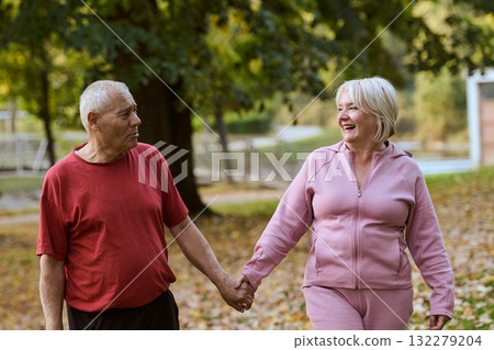 Elderly couple strolling through the breathtaking beauty of nature, maintaining their vitality and serenity, embracing the joys of a health-conscious and harmonious lifestyle Elderly couple strolling through the breathtaking beauty of nature, maintaining their vitality and serenity, embracing the joys of a health-conscious and harmonious lifestyle 132279204