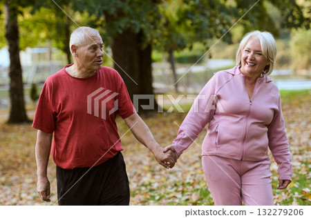 Elderly couple strolling through the breathtaking beauty of nature, maintaining their vitality and serenity, embracing the joys of a health-conscious and harmonious lifestyle Elderly couple strolling through the breathtaking beauty of nature, maintaining their vitality and serenity, embracing the joys of a health-conscious and harmonious lifestyle 132279206