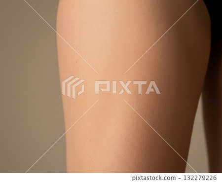 Close-up, textured studio shot of a woman's thigh and hip area, showcasing smooth, even skin texture, ideal for representing a successful cellulite smoothing or body contouring treatment Close-up, textured studio shot of a woman's thigh and hip area, showcasing smooth, even skin texture, ideal for representing a successful cellulite smoothing or body contouring treatment 132279226