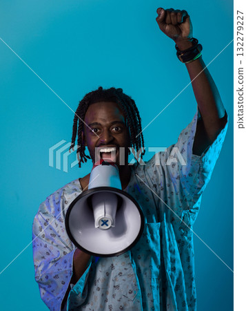 In a powerful and symbolic image, an African American man wears traditional clothing, passionately wields a megaphone against a striking blue background, with his hand raised in the air symbolizing In a powerful and symbolic image, an African American man wears traditional clothing, passionately wields a megaphone against a striking blue background, with his hand raised in the air symbolizing 132279227
