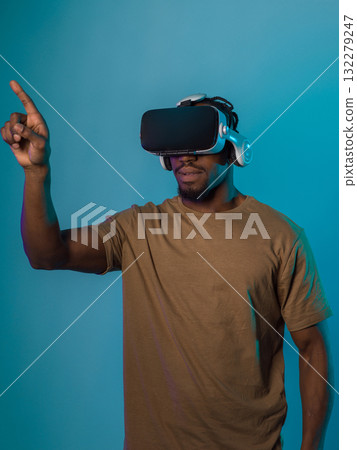 Immersed in a digital realm, an African American man navigates the virtual landscape with a VR goggles, using tactile gestures to interact with virtual objects, showcasing a harmonious blend of 132279247