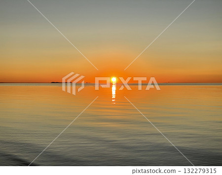 Majestic sunset over the sea. The sun sets casting a golden glow across the water. The sky is painted with bright colors. Sunset beach in summer evening 132279315